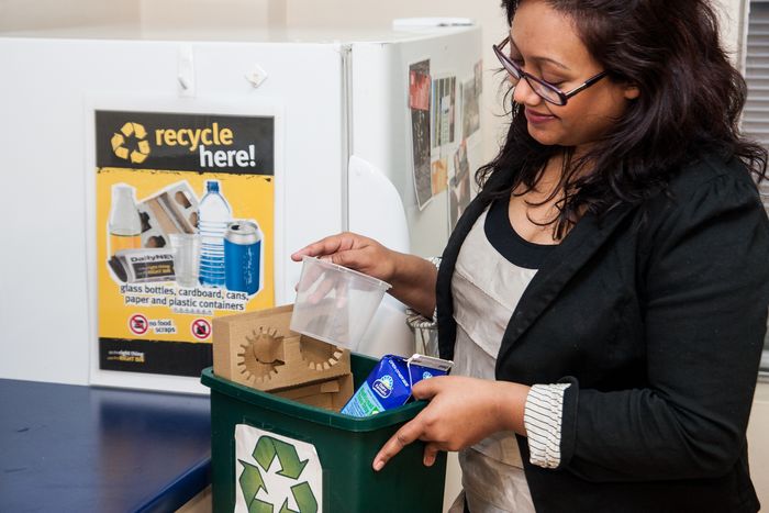 Young woman recycling plastic container in kitchen mixed bin © Zo Zhou